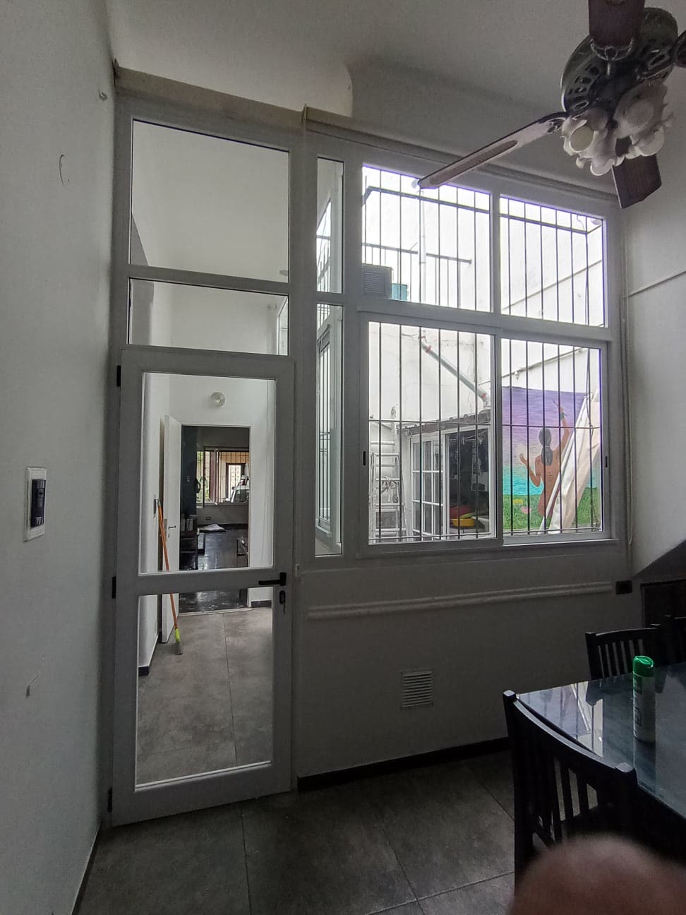 Cerramiento blanco de doble altura con puerta, paños y ventana
