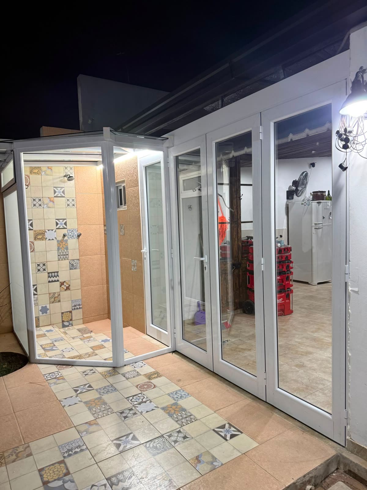 Cerramiento blanco de ducha exterior y puertas plegables de noche
