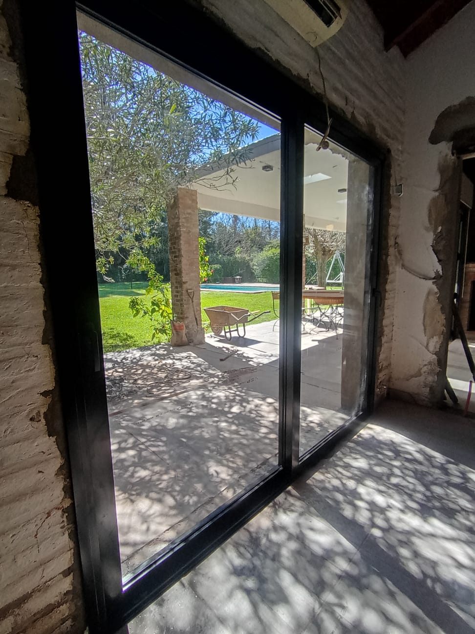 Vista desde adentro por una corrediza negra hacia un jardín con pileta