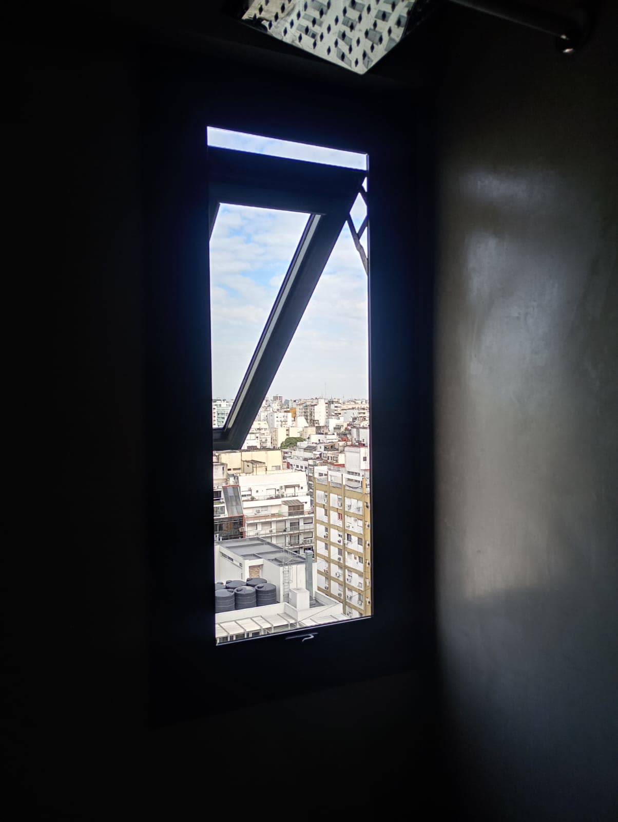 Ventana proyectante negra abierta con vista a la ciudad