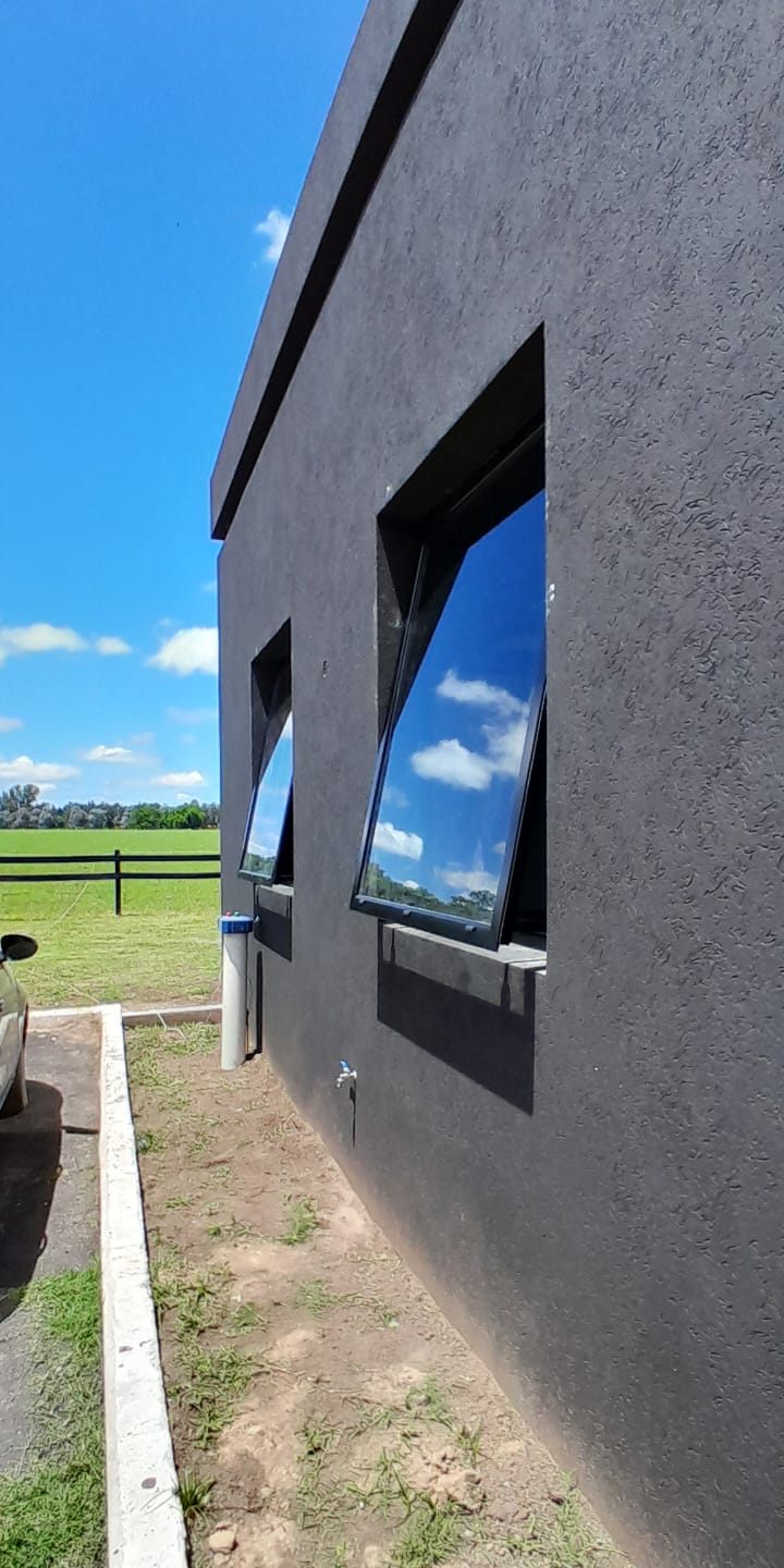 Ventanas proyectantes negras en una fachada oscura, reflejando el cielo