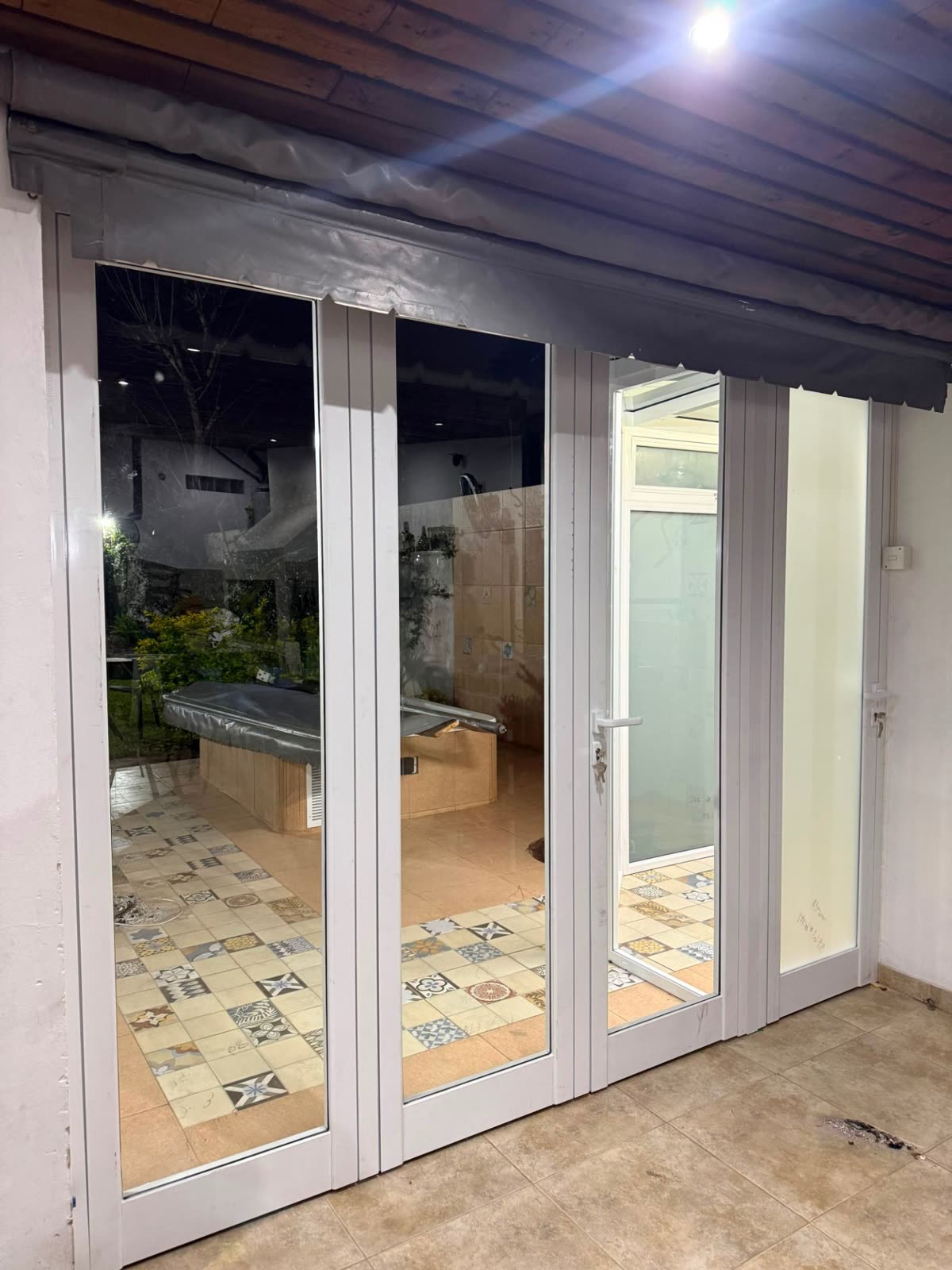 Puertas de aluminio blancas que dan a un quincho con piso calcáreo
