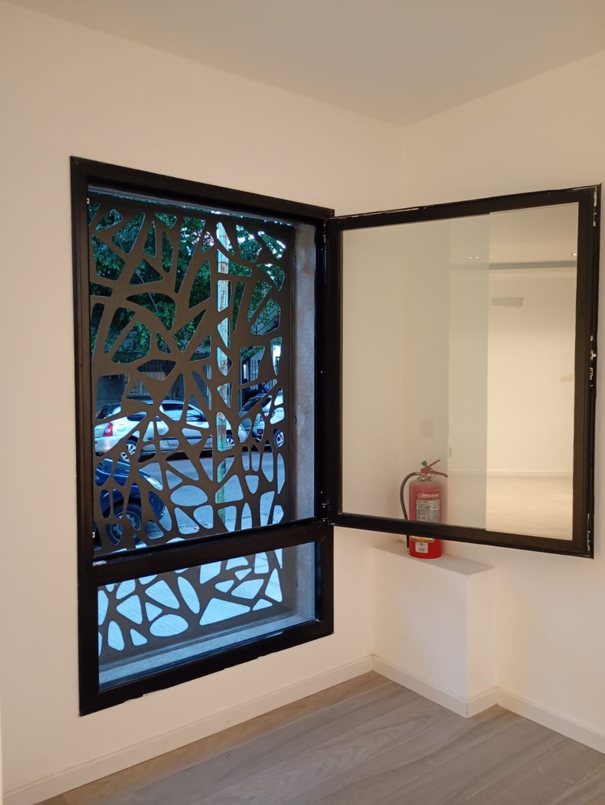 Ventana negra abierta frente a un panel calado